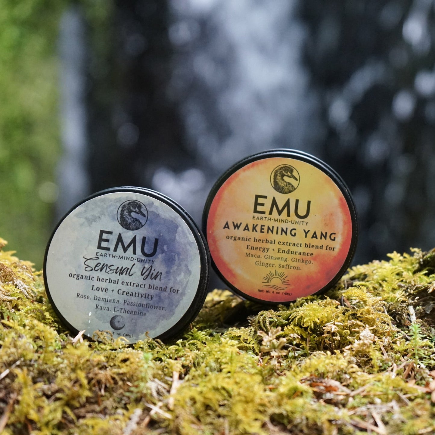 Two EMU product containers on a mossy surface with a blurred natural background