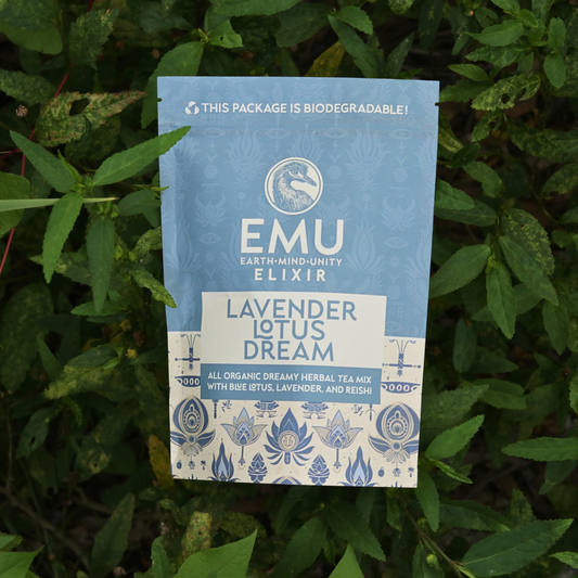 Blue package of EMU Elixir Lavender Lotus Dream tea mix on a green leafy background